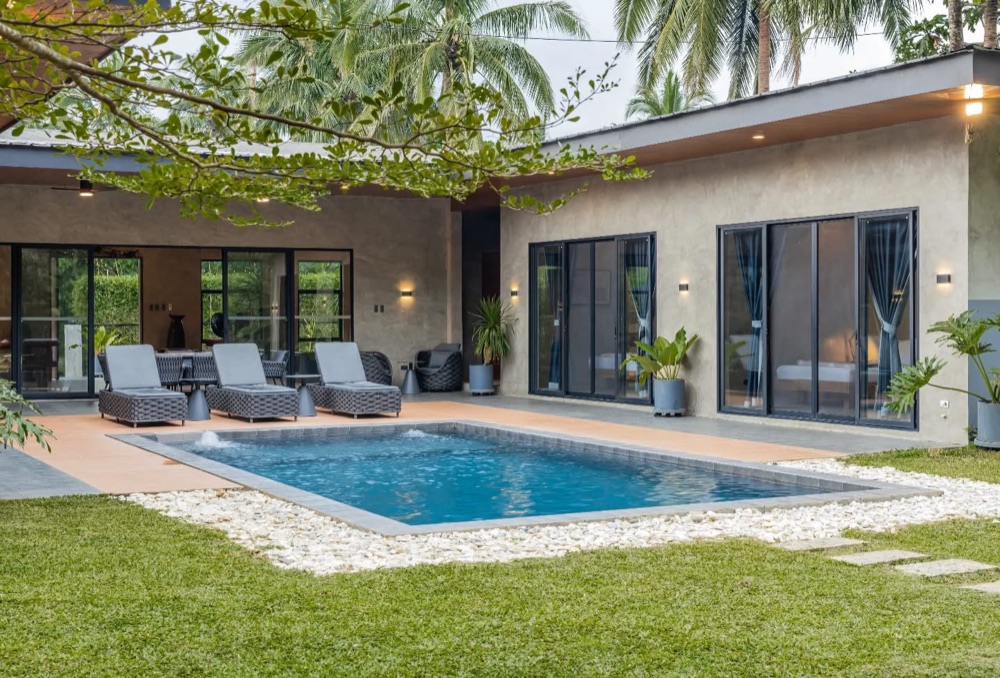 Casa Fariñas — pavilions in textured concrete set around a pool, under coconut palms.