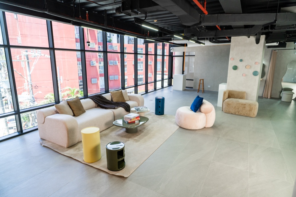 G&R Studio lounge area with soft seating, exposed black ceiling services and a full glazed wall.