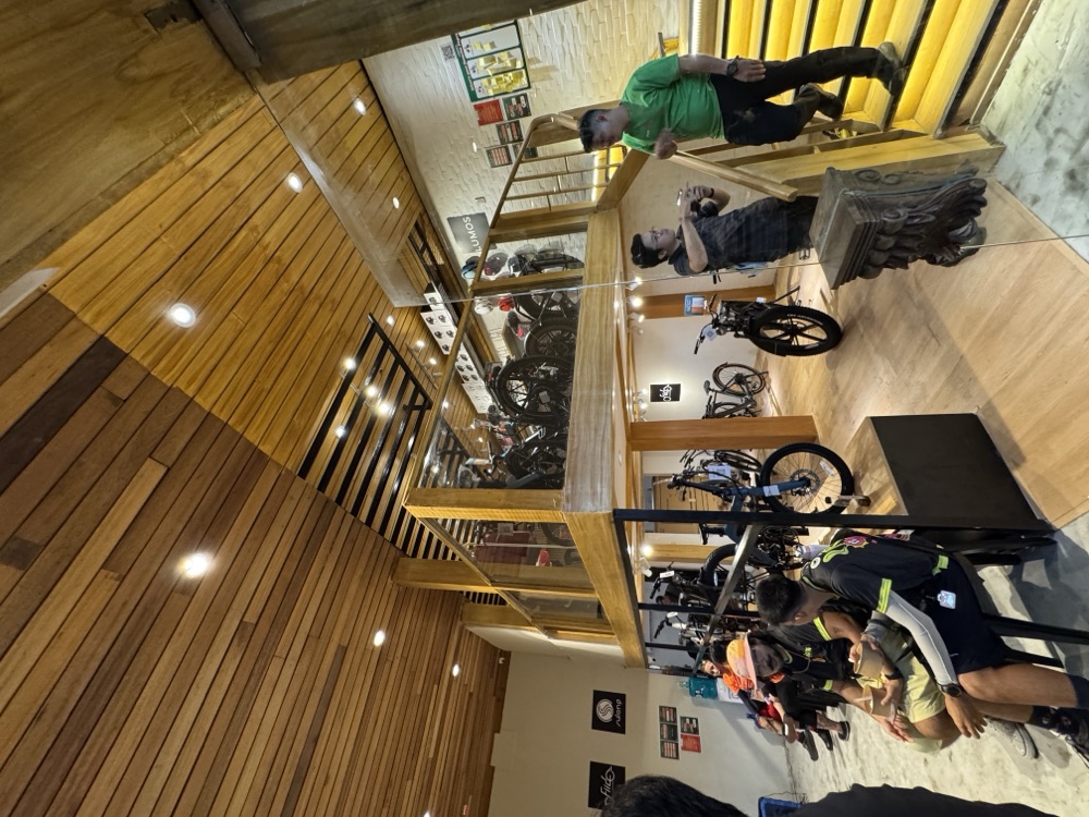 Popcycle GH — bike shop interior with a timber mezzanine and a yellow-lit stair.